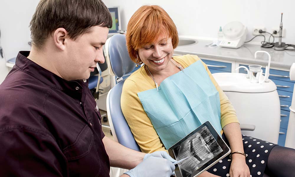 Dentist explaining dental x-rays on iPad to female patient