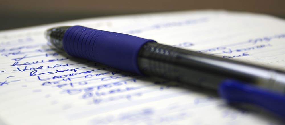 Blue pen and pad with written list