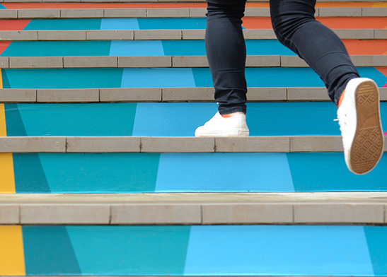 person walking up colorful stairs