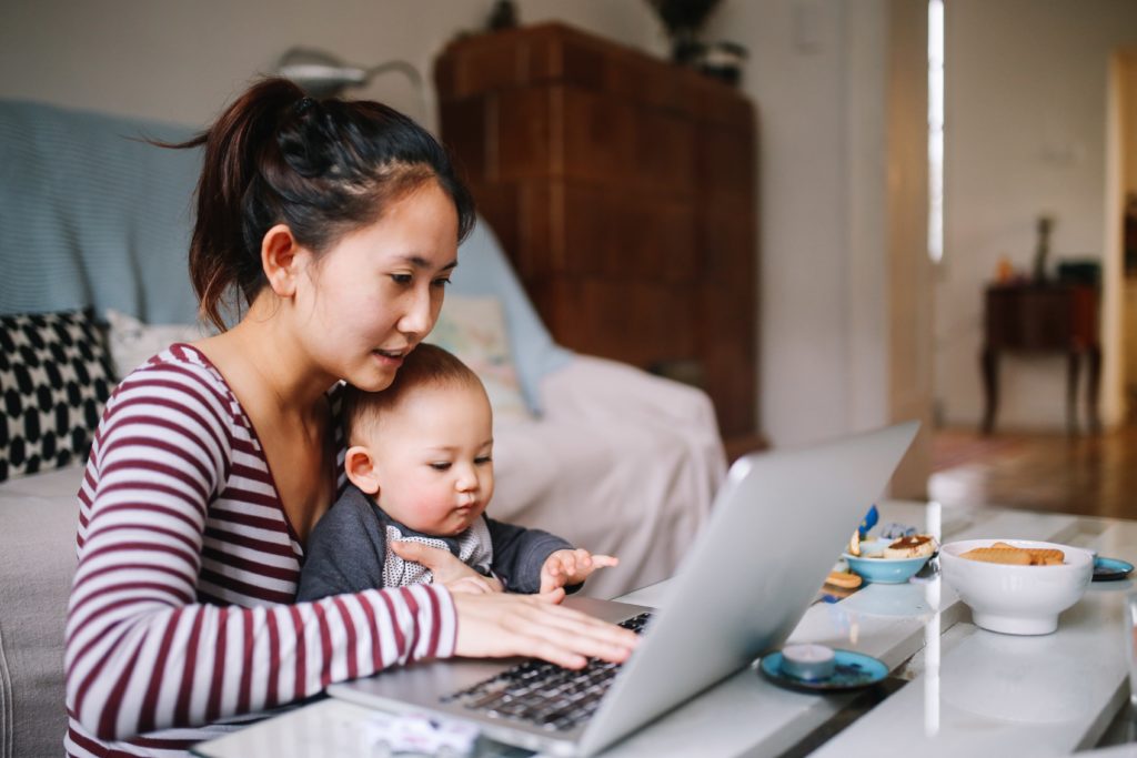 Mom working on a laptop with a baby in her lap