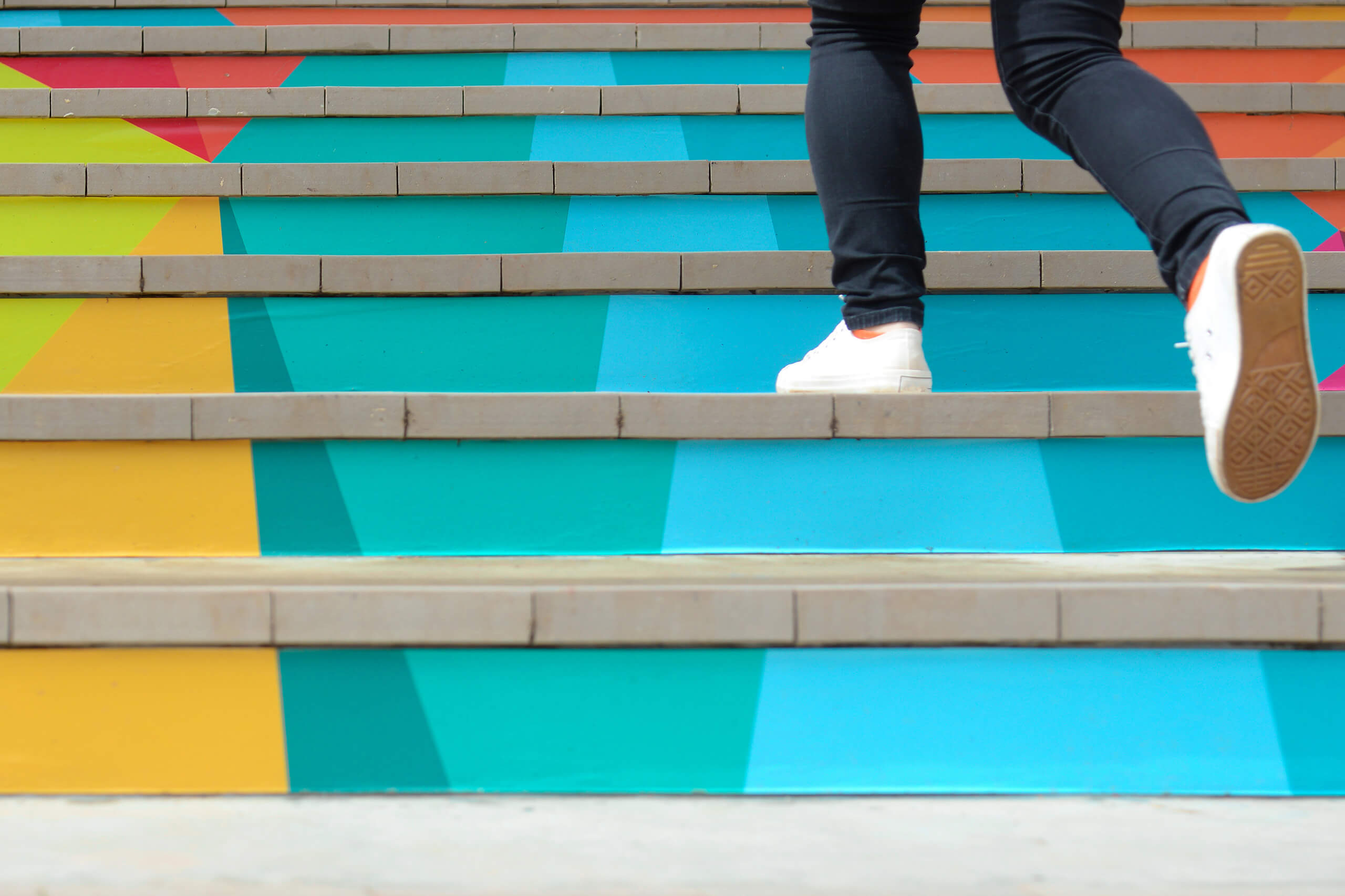 person walking up colorful stairs